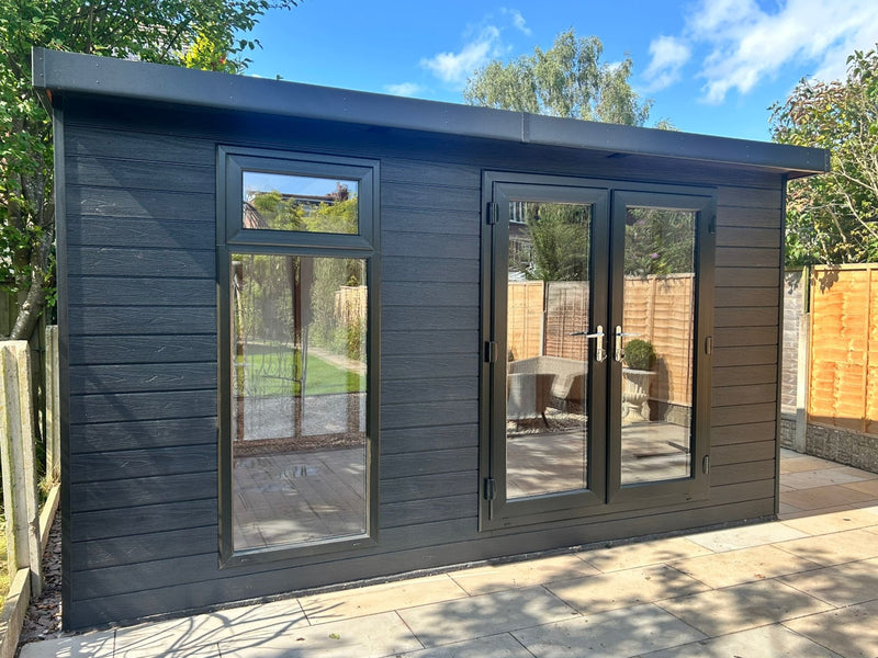Dark grey, wooden garden building with double doors, tall front window. Viewed from the front. 