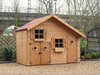 Large wooden children's playhouse with shorter double doors, taller single door, two acrylic windows, viewed from the front/left side. 