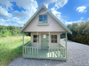 Laurie's Retreat two-storey children's playhouse with a veranda, painted in white and green, viewed from the front