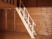 Interior of large wooden playhouse, wooden staircase leading to second level of playhouse. 