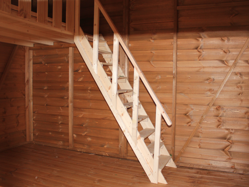Interior of large wooden playhouse, wooden staircase leading to second level of playhouse. 