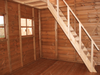 Interior of wooden playhouse, close up of wooden staircase leading to second level. 