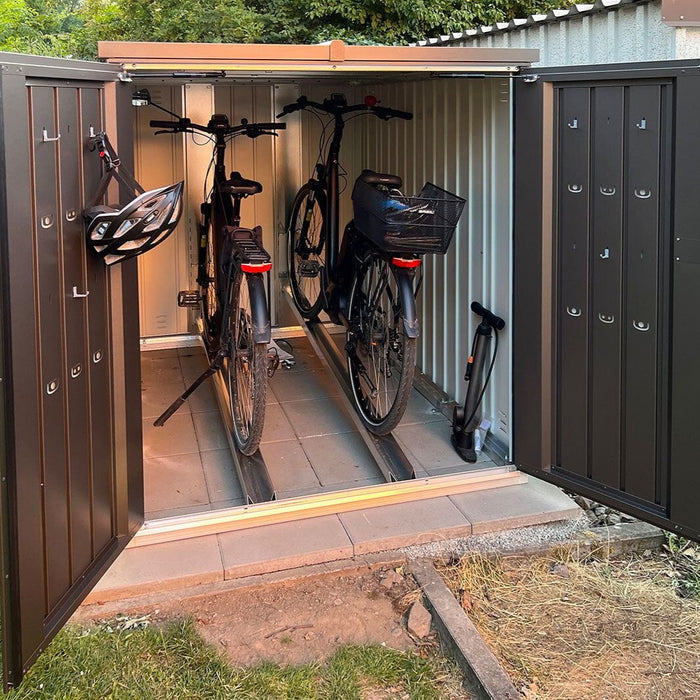 MiniGarage steel outdoor bike store in metallic dark grey finish in a happy customers garden