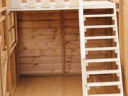 Close up of wooden staircase leading to the 2nd level of wooden playhouse.