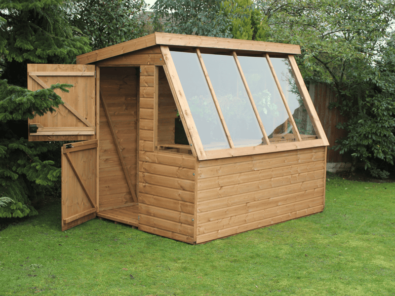 Wooden potting shed with long slanted windows, staging under windows, open stable split door. Viewed from the front/left side.