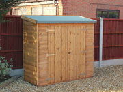 Small wooden tool shed with double doors, viewed from the left/front. 