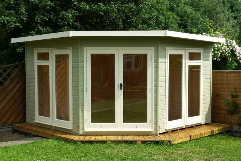 A corner pent-style roof garden building with full pane windows and a painted exterior.