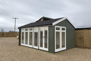 A traditional styled garden room with a pitched roof, situated outdoors, with a lot of windows and a set of double doors.