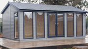 A traditional styled garden room with a pitched roof and large windows, presented in a grey color.