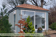 A traditional hip roof garden building with sliding doors, painted in urban field with a shingled roof.